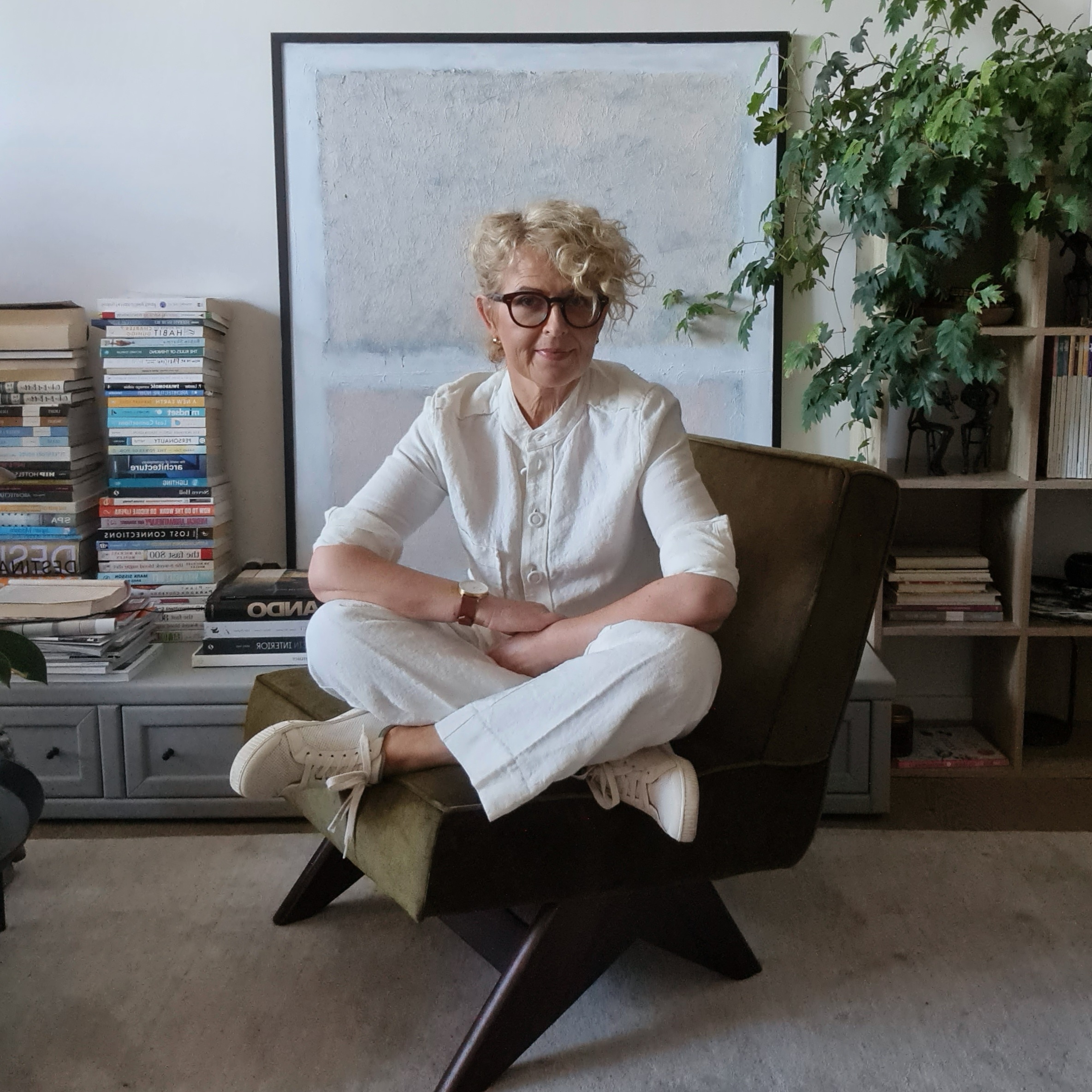 Teresa Pokorski seated in her design studio beside books, artwork and greenery