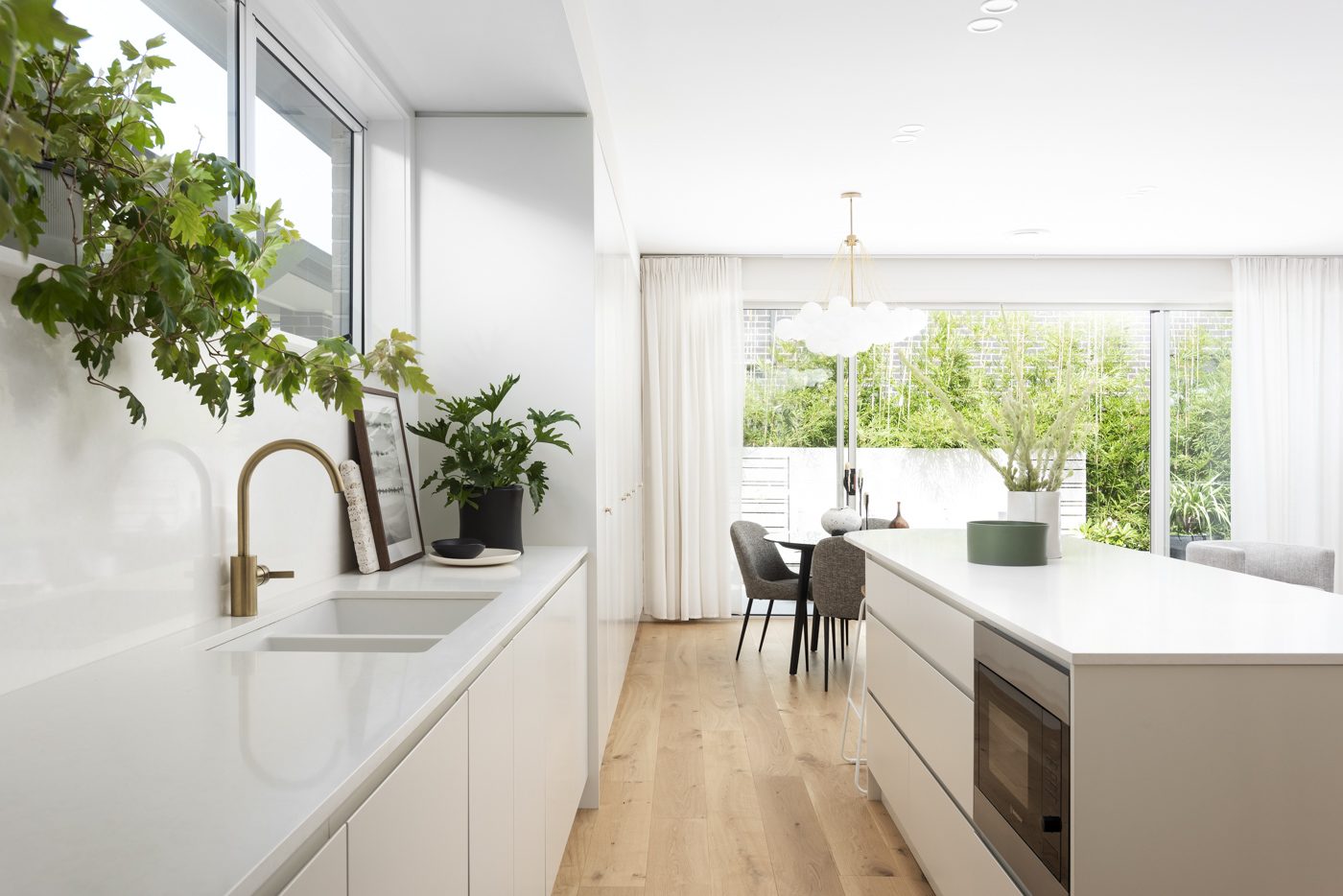 A light-filled Margaux Homes kitchen opening through to the dining room and a green courtyard