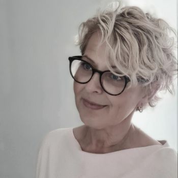 A woman wearing glasses and a white shirt.